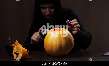 Junge Brünette Frau schnitzt einen Kürbis für Halloween Vorbereitung Stockfoto