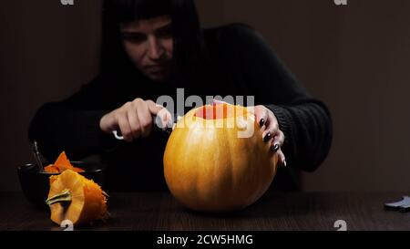 Junge Brünette Frau schnitzt einen Kürbis für Halloween Vorbereitung Stockfoto