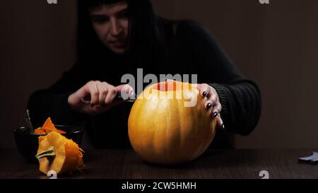 Junge Brünette Frau schnitzt einen Kürbis für Halloween Vorbereitung Stockfoto
