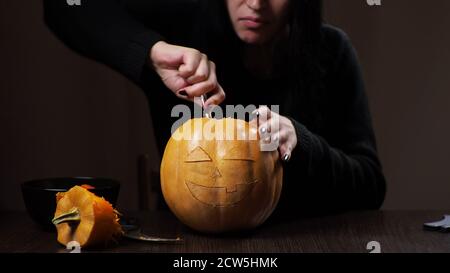 Junge Brünette Frau schnitzt einen Kürbis für Halloween Vorbereitung Stockfoto