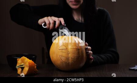 Junge Brünette Frau schnitzt einen Kürbis für Halloween Vorbereitung Stockfoto