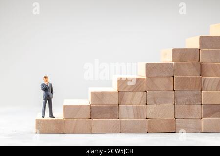 Karriereleiter. Tritt als Symbol des Weges zum Ziel auf. Man in Suit steht am Anfang des Weges zum erfolgreichen Ziel. Stockfoto