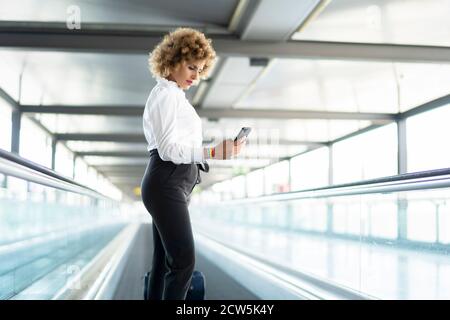 Stewardess in weißem Hemd mit ihrem Smartphone Stockfoto
