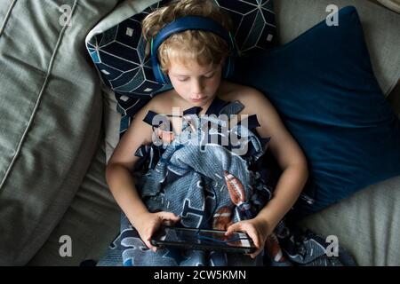 Overhead-Ansicht von Young Boy in Kopfhörer auf Tablet-Computer Stockfoto