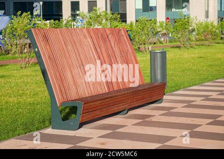 Moderne Holzbank mit hoher Lehne und einem schlichten Design in der Innenstadt von Esplanade. Stockfoto