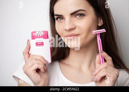 Eine Frau verwendet einen Epilierer und Rasierer, um Haare zu entfernen Stockfoto