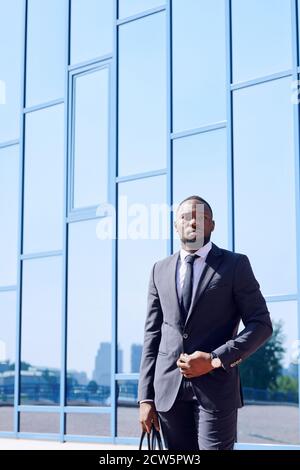 Junge afrikanische Business-Profi in formalwear steht gegen Gebäude Stockfoto