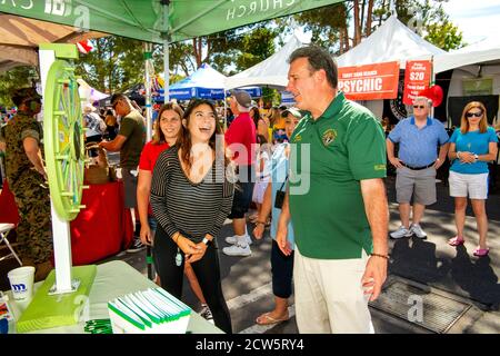 Ein katholischer Diakon gesellt sich mit jungen Gemeindemitgliedern an einem Rad des Zufalls während einer überdachten Straßenmesse Outreach-Ausstellung in Laguna Niguel, CA. Stockfoto