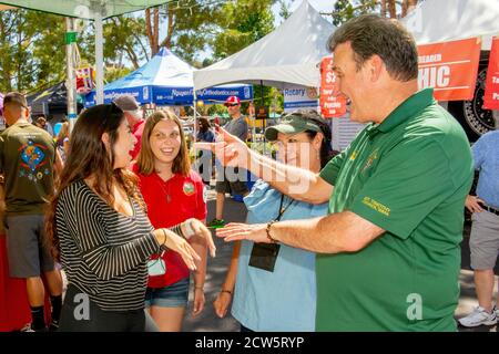 Ein katholischer Diakon gesellt sich mit jungen Gemeindemitgliedern während einer Straßenmesse Outreach-Ausstellung in Laguna Niguel, CA. Stockfoto