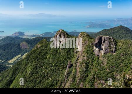 Fernsicht auf die atemberaubenden drei Felsenformationen Gipfel mit Serra do Mar grüne Vegetation mit Carioca Bucht Küste im Hintergrund bedeckt. Stockfoto