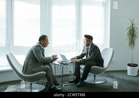 Zwei selbstbewusste reife Geschäftsleute in formalwear diskutieren Arbeitsmomente Stockfoto