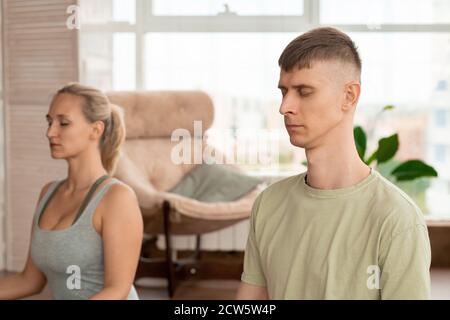 Junger entspannter Sportler in aktivem Ohr, der die Augen während der Meditation geschlossen hält Stockfoto