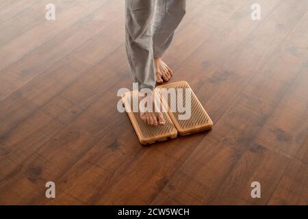 Beine von jungen aktiven barfuß Mann in grauen Sportspants stehend Auf Yoga-Pads Stockfoto