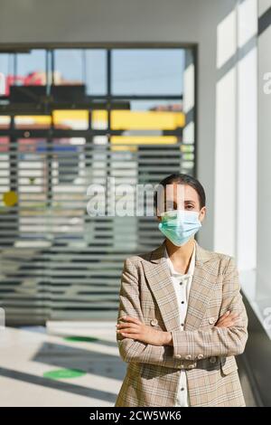 Vertikale Taille bis Porträt des zuversichtlich Geschäftsfrau trägt Maske, während mit Armen im Sonnenlicht gekreuzt stehen, kopieren Raum Stockfoto