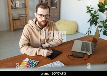 Junge zeitgenössische seriöse männliche freiberufliche Designer retuschieren Bilder Stockfoto