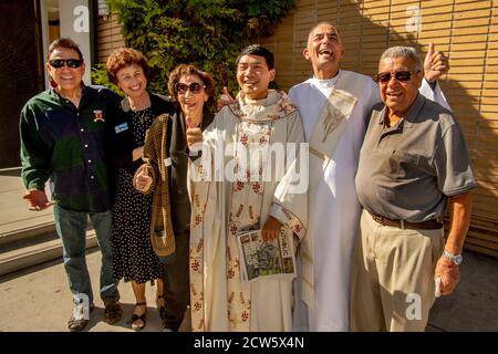 Nach der Messe posiert der Diakon einer katholischen Kirche in Südkalifornien mit seinem asiatisch-amerikanischen Priester und multirassischen Gemeindemitgliedern in der Kirche Outdoo Stockfoto