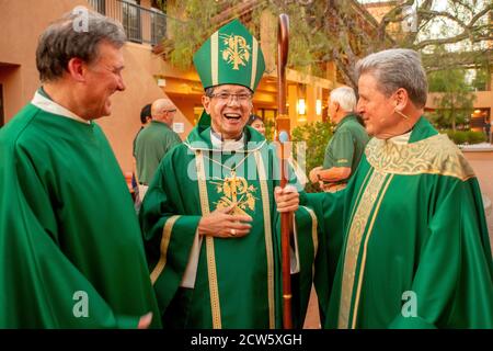 In grünen zeremoniellen Gewändern teilen sich der Diakon und monsignore einer katholischen Kirche in Südkalifornien einen Witz mit einem asiatischen amerikanischen Bish Stockfoto