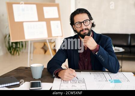 Glücklich junge bärtige männliche Entwickler von mobilen Anwendungen machen neue Skizze Stockfoto