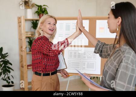 Zwei erfolgreiche Geschäftsfrauen in smarter Casualwear, die sich gegenseitig hoch bringen Fünf Stockfoto
