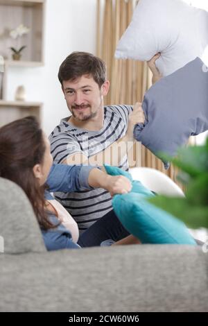 Pärchen, die auf dem Sofa eine Kissenschlacht haben Stockfoto