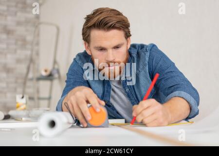 Junger Mann mit Bart und Metallband messen bei der Arbeit Stockfoto