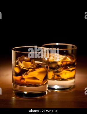 Zwei Gläser Whisky auf den Felsen auf einem Holz Tisch auf schwarzem Hintergrund Stockfoto