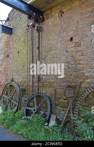 Ein Paar große Kettenzüge auf einem großen Stahlträger, der zwischen zwei Scheunen auf einer Farm in Cumbria, Großbritannien, hängt Stockfoto