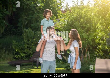 Vater hält Sohn auf den Schultern, seine Frau berührt seine Hand Stockfoto