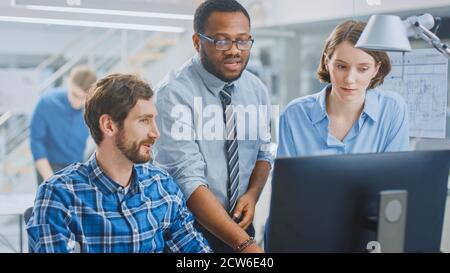 In der Industrial Engineering Facility: Portrait des gutaussehenden männlichen Ingenieurs, der am Desktop-Computer arbeitet, Chefingenieurin und Projektmanagerin Stockfoto