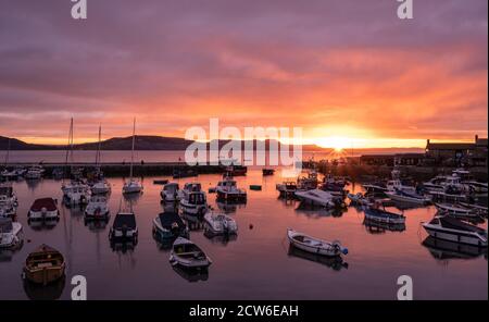 Lyme Regis, Dorset, Großbritannien. September 2020. UK Wetter: Der Himmel leuchtet mit Herbstfarbe, wie die Sonne über dem Cobb aufgeht, Lyme Regis an einem kühlen Septembermorgen. Kredit: Celia McMahon/Alamy Live Nachrichten Stockfoto