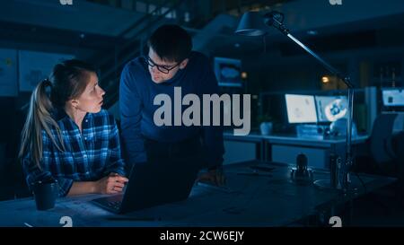 Industrial Engineering Einrichtung: Weibliche Ingenieurin arbeitet am Desktop-Computer, Projektmanagerin steht neben und erklärt die Besonderheiten der Aufgabe und Stockfoto