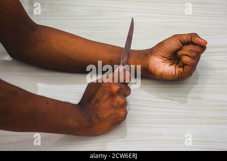 Committed Suicide Konzept - man will Selbstmord begehen, indem er seine Adern mit Messer in isoliert auf dem Boden Hintergrund. Man Selbstmord durch Messer schneiden ein Stockfoto