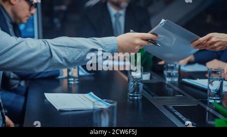 Im Corporate Meeting Room Close-up auf die Hände der Geschäftsleute Pässe Folder mit wichtigen Dokumenten. Vertragsunterzeichnung Konzept. Menschen Stockfoto