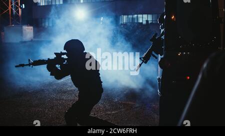 Silhouette eines maskierten Teams bewaffneter SWAT-Polizeibeamter Verlassen Sie einen schwarzen Van, der vor einem Bürogebäude geparkt ist. Soldaten mit Gewehren und Taschenlampen Stockfoto