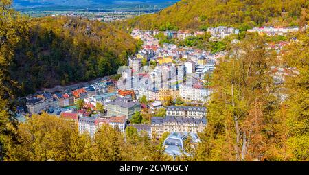 Karlovy Vary Stadt Luftpanorama mit bunten bunten bunten Gebäuden und Spa-Hotels in der Altstadt. Panorama von Karlsbad Stadt und Slavkov Wald Hügel mit Bäumen am Hang im Herbst Stockfoto