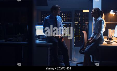 Spät in der Nacht im Corporate Office zwei Young Professionals freundlich chatten, News austauschen, über Job reden, Flirten Stockfoto