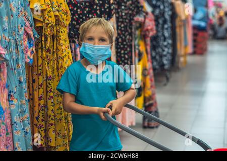 Eine neue Normalität. Kaukasischen Jungen in Sanitär Gesichtsmaske Einkaufen im Supermarkt. Kind mit Einkaufskorb. Kind trägt Schutz gegen Coronavirus Stockfoto