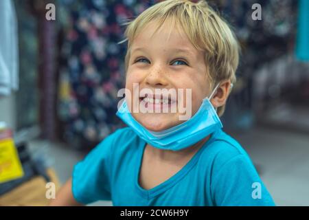 Porträt schließen niedlich lächelnd blauäugig Sommersprossen blonde junge künstlerische Mimik, Gesten tragen Sanitär Gesichtsmaske Einkaufen Supermarkt. Neu Stockfoto