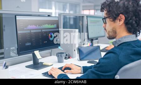 Young Handsome Manager mit Curly Hair arbeitet auf einem Desktop-Computer in Buchhalter Software. Vielfältige und motivierte Geschäftsleute arbeiten an Computern Stockfoto