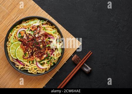 Birmanischer Atho in schwarzer Schale auf dunkler Schieferplatte. Atho ist myanmar indische Küche Gericht beliebt in Chennai. Asiatische Speisen und Gerichte. Draufsicht. Speicherplatz kopieren Stockfoto