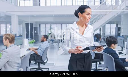 Schöne Managerin ist Walking Pass ihre Business Kollegen und überwachen ihre Arbeit. Vielfältige und motivierte Geschäftsleute arbeiten an Computern Stockfoto