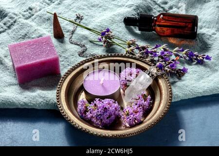 Aromathreapy Konzept. Ätherisches Öl, Seife, Duftkerze, Weihrauchkegel, Parfümfläschchen mit Lavendel und vervain Blumen auf blauem Hintergrund Stockfoto