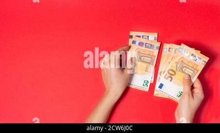 Der Mann hält das Geld der Banknote 50 Euro auf einem roten Hintergrund. Kredit, Geldkonto, Ersparnisse Stockfoto