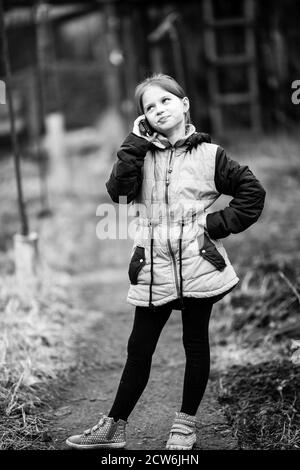 Zehn-jährige Mädchen im Gespräch am Telefon im Freien stehen. Schwarzweiß-Fotografie. Stockfoto