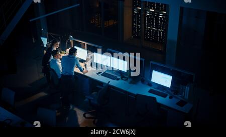 Spät in der Nacht in Modern Office: Diverse Team von erfolgreichen Geschäftsleuten und Geschäftsleute versammeln sich rund um Computer, haben Diskussion, Problem zu finden Stockfoto