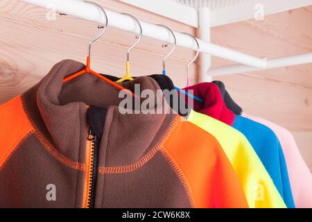 Bunte Fleece-Jacken hängen an Kleiderbügeln, Nahaufnahmen mit selektivem Fokus Stockfoto