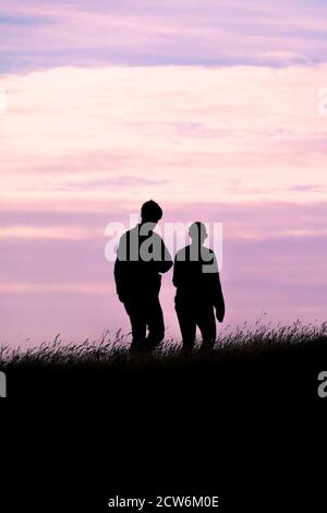 Zwei Spaziergänger, die durch die späte Abendsonne silhouetted werden. Stockfoto