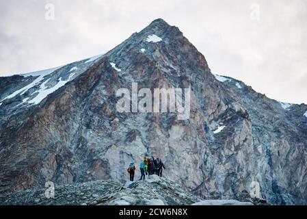 Zinal, Schweiz - 19. Juli 2019: Rückansicht des Wanderteams mit Rucksäcken, der auf einem felsigen Weg zum Gipfel geht. Konzept von Reisen, Wandern und Bergsteigen. Stockfoto