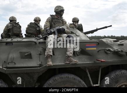 Flagge Armeniens auf einem gepanzerten Personenkräger und Soldaten mit Maschinengewehren. Militärischer Konflikt im Kaukasus. Collage. Stockfoto