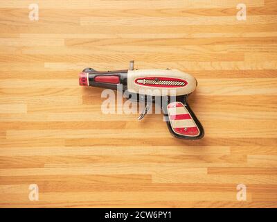 Zinn Spielzeugpistole mit einem Holztisch Hintergrund Stockfoto